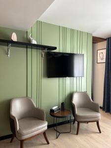 a living room with two chairs and a flat screen tv at Empire City in Karagandy +25 photos