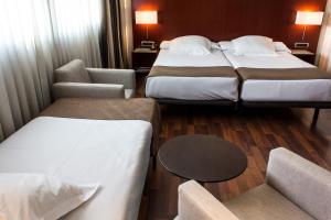a hotel room with two beds and a chair at Zenit Valencia in Valencia