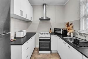 a kitchen with white cabinets and a stove top oven at Walk to Beach And Cafes Near City And Airport in West Beach