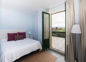 a bedroom with a bed and a door to a balcony at Hotel Valle del Oja in Casalarreina