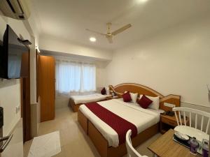 a bedroom with two beds and a table and a television at Zipp Lite - HAL Old Airport Road in Bangalore