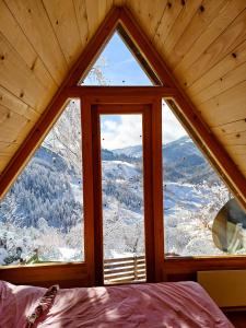 a bedroom with a large window in a cabin at Wooden House ŠUŠKA 3 - Drvena kuća ŠUŠKA 3 in Zaovine
