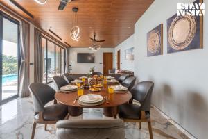 a dining room with a wooden table and chairs at StayVista's Esperanza - Mountain-Side Retreat with Infinity Pool, Jacuzzi, Gazebo & Indoor-Outdoor Activities in Lonavala