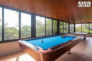 a pool table in a room with windows at StayVista's Esperanza - Mountain-Side Retreat with Infinity Pool, Jacuzzi, Gazebo & Indoor-Outdoor Activities in Lonavala
