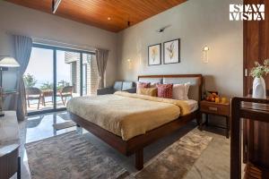 a bedroom with a large bed and a balcony at StayVista's Esperanza - Mountain-Side Retreat with Infinity Pool, Jacuzzi, Gazebo & Indoor-Outdoor Activities in Lonavala +31 photos