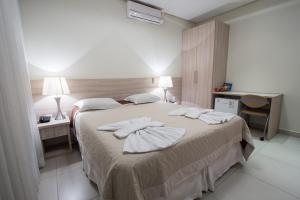 a bedroom with a large bed with towels on it at Hotel Villa de Holanda in Holambra