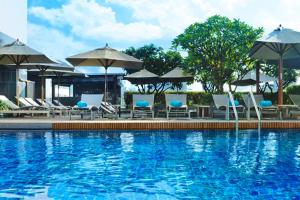 a swimming pool with lounge chairs and umbrellas at Le Meridien Bangkok in Bangkok