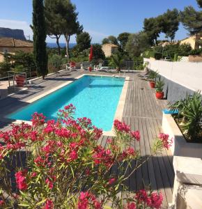 a swimming pool with pink flowers in a yard at Le petit cassis vue mer appartement 70m2 dans villa in Cassis