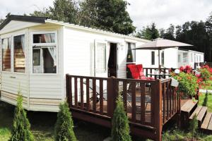 biała przyczepa kempingowa z tarasem i parasolem w obiekcie Mobile home in Kolczewo with a terrace w mieście Kołczewo