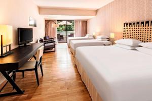 a hotel room with four beds and a desk and a computer at Sheraton Rhodes Resort in Ixia