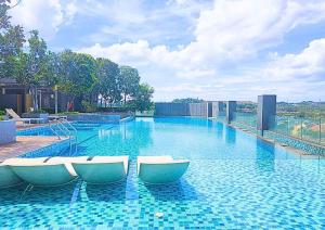 a swimming pool with four chairs in the water at Cozy Urban Retreat in Emira, Mall Next Door #EM1 in Shah Alam