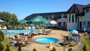 a patio with chairs and tables and a swimming pool at Brydar with Sauna, Swimming Pool and Jacuzzi in Mielno