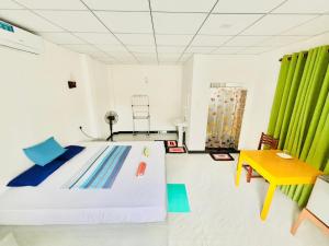 una camera con letto, tavolo e tende verdi di Viraj's Garden a Tangalle