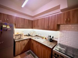 eine Küche mit Holzschränken und einem Edelstahlkühlschrank in der Unterkunft The Cozysweet Homestay in Manila