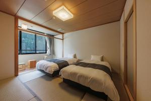 una camera da letto con due letti e una finestra di 南紀月の瀬温泉ぼたん荘 a Takaike Altre 37 foto