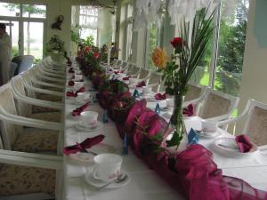 a long table with white tables and chairs with flowers at Hotel & Waldrestaurant Johannesruh in Wesenberg