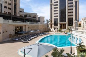 an outdoor swimming pool with chairs and an umbrella at Residence Inn by Marriott Algiers Bab Ezzouar in Alger