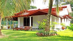 a house with a bench and a palm tree at Maali holiday Apartments in Hiriketiya