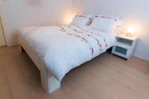 een slaapkamer met een groot wit bed en een bijzettafel bij 7even in Vrouwenpolder