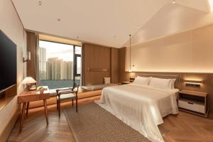 een slaapkamer met een bed, een bureau en een raam bij Papuman hotel in Kunming