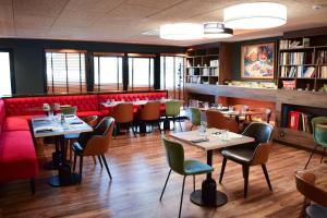 ein Restaurant mit Tischen und Stühlen und einer roten Couch in der Unterkunft Best Western Plus Le Conquerant Rouen Nord in Bois-Guillaume