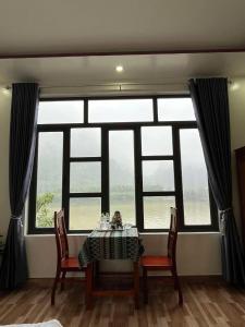 a table and chairs in a room with a large window at Duong Riverside Homestay in Phong Nha