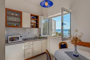 a kitchen with a table and a microwave and a window at Apartment Tafra 4 in Lokva Rogoznica