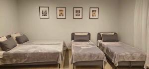 three beds in a room with pictures on the wall at Sodyba Azagis in Vilkanastrai