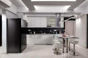 a kitchen with white cabinets and a table with stools at Rhodes Skyline Suite with In Door Jacuzzi Sea View in Ixia