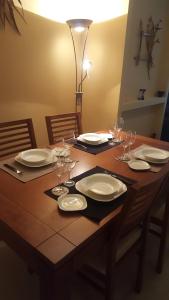 a wooden table with plates and wine glasses on it at Appartamento Sinestesia Oceanica in Puerto del Rosario
