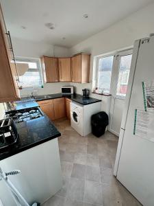 a kitchen with a white refrigerator and a dishwasher at Smart and Chic 2 bed Apartment in London