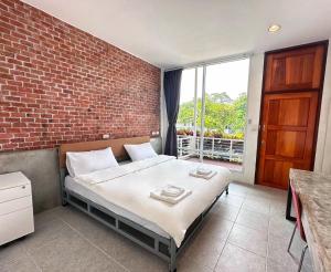 a bedroom with a bed and a brick wall at Woodview Resort in Samut Prakan