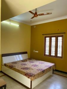 a bed in a room with a ceiling fan at Magizh Kudil in Pūrnānkuppam