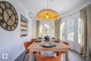 ein Esszimmer mit einem Holztisch und einer großen Uhr in der Unterkunft Villa Buena Vida by Abahana Villas in Jávea