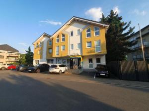 a yellow building with cars parked in a parking lot at 17 Apartments und 2 Suiten in Zwingenberg +2 photos