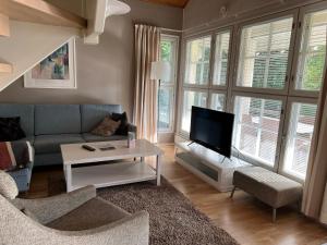 a living room with a couch and a tv at Katinkulta Apartments in Vuokatti