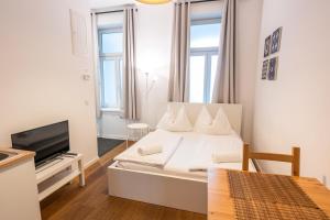 a white bedroom with a bed and a tv at Vienna City Apartments - Metro 1160 Vienna in Vienna