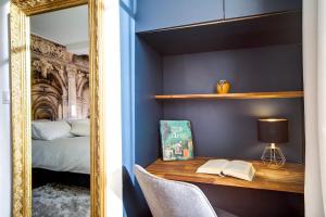 a mirror reflecting a bedroom with a desk and a bed at La Suite du Roi Henri in Vendôme