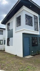 a white house with a blue door and windows at Lubrin Townhouse in San Pablo