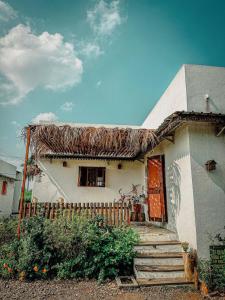a small white house with a thatch roof at 2-BHK 'Nature's Haven Farmhouse' Pune-baramati Highway in Sāngwi +18 photos