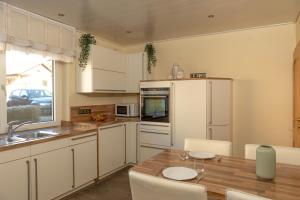 a kitchen with a wooden table and white cabinets at Ferienwohnung MiA in Frankenau