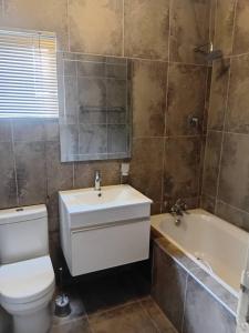 a bathroom with a toilet and a sink and a tub at AYA Apartment in Maun +8 photos
