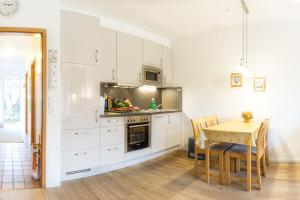 a kitchen with white cabinets and a table and a dining room at Lütje Seute in Böhl