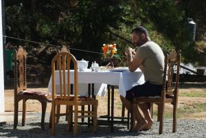 un hombre sentado en una mesa frente a una mesa con en Panorama Accommodations Nuwara Eliya en Nuwara Eliya