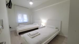 a white room with two beds and a window at Apartamento Billa d Aro in Haro