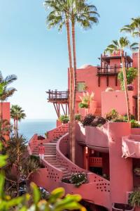 a pink building with palm trees and the ocean at The Ritz-Carlton Tenerife, Abama in Guía de Isora