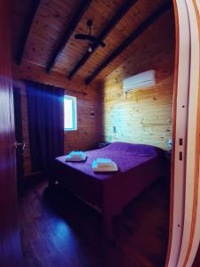 a bedroom with a bed in a wooden cabin at Cabaña Las Martinetas in María Grande