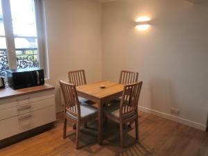 a dining room with a table and four chairs at 2P refait à neuf, calme, quartier historique, entre seine et cathédrale in Mantes-la-Jolie +3 photos