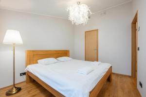 a bedroom with a bed with white sheets and a chandelier at Modern city center apartment in Tartu