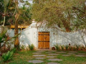a white building with a wooden door in a yard at Kara Fort Kochi in Fort Kochi +16 photos